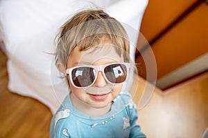 Portrait of happy smiling adorable toddler in baby sunglasses. cheerful child playing