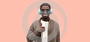 Portrait of happy smiling african man in wireless headphones listening to music and showing gesture thumbs up as like sign