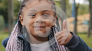 Portrait happy smiling afro american schoolgirl little girl african showing thumb up like support gesture symbol