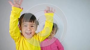 Portrait of a happy smiling Asian child girl and her older sister moody behind isolated on white background.