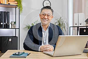 Portrait of happy smiling Asian Chinese business man at home office look away turn head at camera