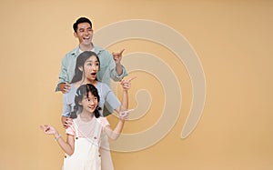 Portrait happy smiling Asian family hugging and pointing finger isolated on color copy space background