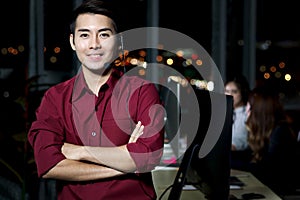 Portrait of happy smiling Asian handsome man with headphones standing with arms crossed, work night shift at call center customer