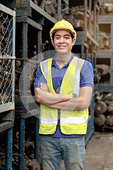 Portrait of happy smiling Asian industrial engineer worker man with safety vest and helmet standing with arms crossed at