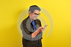 Portrait of happy smiling Asian man using smartphone wearing casual t-shirt and jacket with eyesglasses