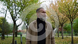 Portrait of happy smiling attractive mature man looking around autumn park.