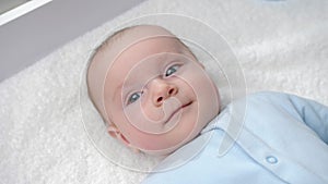 Portrait of happy smiling baby boy with blue eyes smiling on dressing table. Concept of hygiene, baby care and