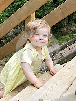 Portrait of happy smiling baby girl outdoors. Little toddler child with blond hairs looking and smiling at the camera
