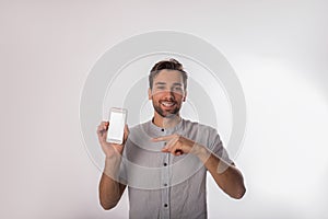 Portrait of a happy smiling bearded man successful entrepreneur holding in hand mobile phone