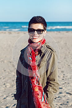 Portrait of happy smiling beautiful Caucasian white brunette woman with short hair in green jacket, red scarf and sunglasses