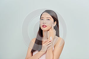 Portrait of happy smiling beautiful young woman touching skin or applying cream, isolated over white background