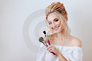 Portrait of happy smiling blonde woman with long wavy hair style holding brush.
