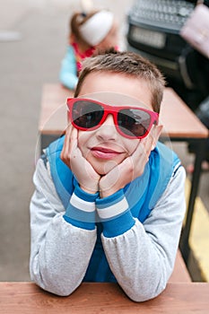 Portrait happy smiling boy in red sunglasses in city