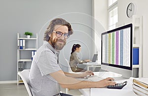 Portrait of happy smiling business accountant sitting at office desk with computer