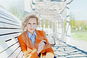 Portrait of happy smiling business woman or fashion girl student with sunglasses sitting on the bench in park outdoor