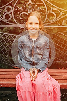 Portrait happy smiling candid eight year old kid girl face sits on bench in nature. prepubertal age of children and lives, mind ps