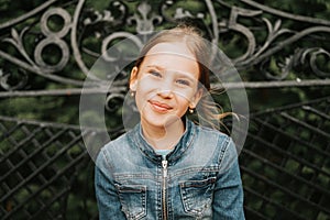 Portrait happy smiling candid eight year old kid girl face sits on bench in nature. prepubertal age of children and their lives, m