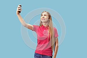 Portrait of a happy smiling casual girl showing blank screen mobile phone isolated over blue background