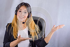Portrait of happy smiling cheerful young support phone operator in headset showing copy space area or something