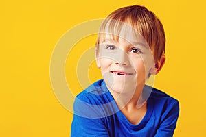 Portrait of a happy smiling child over yellow background. Child loss his baby teeth. Happy and healthy childhood. Cute blond boy
