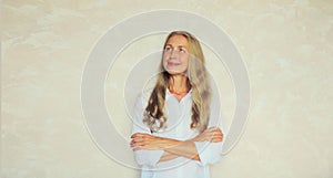 Portrait of happy smiling confident middle-aged woman with crossed arms looks away. Female mature caucasian model in casual white