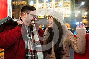 Portrait of happy smiling couple with Christmas presents in the city. Shopping sale people concept