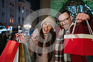 Portrait of happy smiling couple with Christmas presents in the city. Shopping sale people concept