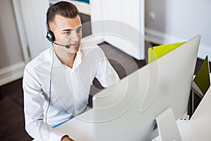 Portrait of happy smiling customer support phone operator at workplace. Call center