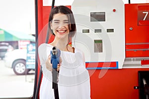 Portrait of happy smiling customer woman holding fuel petrol pump nozzle against for filling up her car, beautiful young lady