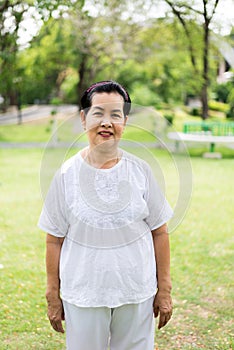 Portrait of a happy and smiling elderly asian woman standing at public park