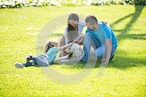Portrait of a happy smiling family with pet dog relaxing in park.