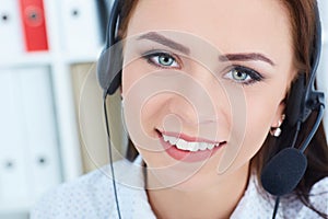 Portrait of happy smiling female customer support phone operator with headset on head at workplace.