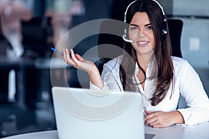 Portrait of happy smiling female customer support phone operator at workplace.