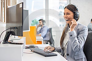 Portrait of happy smiling female customer support phone operator at workplace