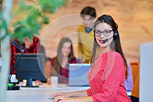 Portrait of happy smiling female customer support phone operator at workplace.