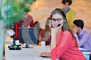 Portrait of happy smiling female customer support phone operator at workplace.