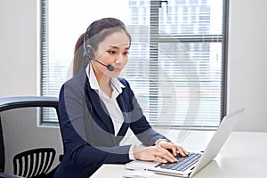 Portrait of happy smiling female customer support phone operator at workplace. Asian