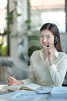 Portrait of happy smiling female customer support phone operator at workplace. Asian