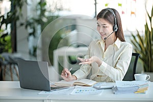 Portrait of happy smiling female customer support phone operator at workplace. Asian