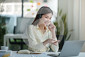 Portrait of happy smiling female customer support phone operator at workplace. Asian