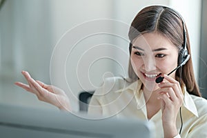 Portrait of happy smiling female customer support phone operator at workplace. Asian