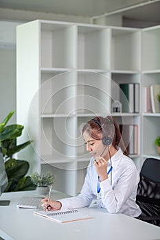 Portrait of happy smiling female customer support phone operator at workplace. Asian