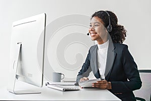 Portrait of happy smiling female customer support phone operator at workplace. Smiling beautiful African American woman