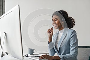 Portrait of happy smiling female customer support phone operator at workplace. Smiling beautiful African American woman