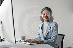 Portrait of happy smiling female customer support phone operator at workplace. Smiling beautiful African American woman