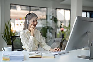 Portrait of happy smiling female customer support phone operator at workplace. Smiling beautiful Asian woman working in