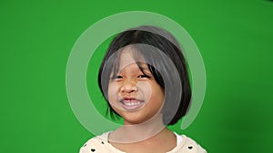 Portrait of happy, smiling, and funny Asian child girl on green screen background, a child looking at camera. Preschool kid