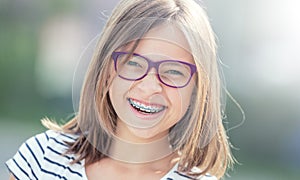 Portrait of happy smiling girl with dental braces and glasses