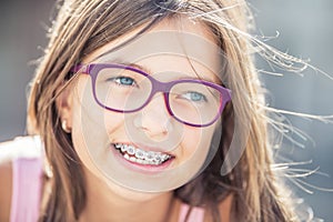 Portrait of happy smiling girl with dental braces and glasses photo