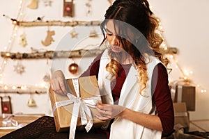 Portrait of a happy smiling girl in dress opening present box  over white background